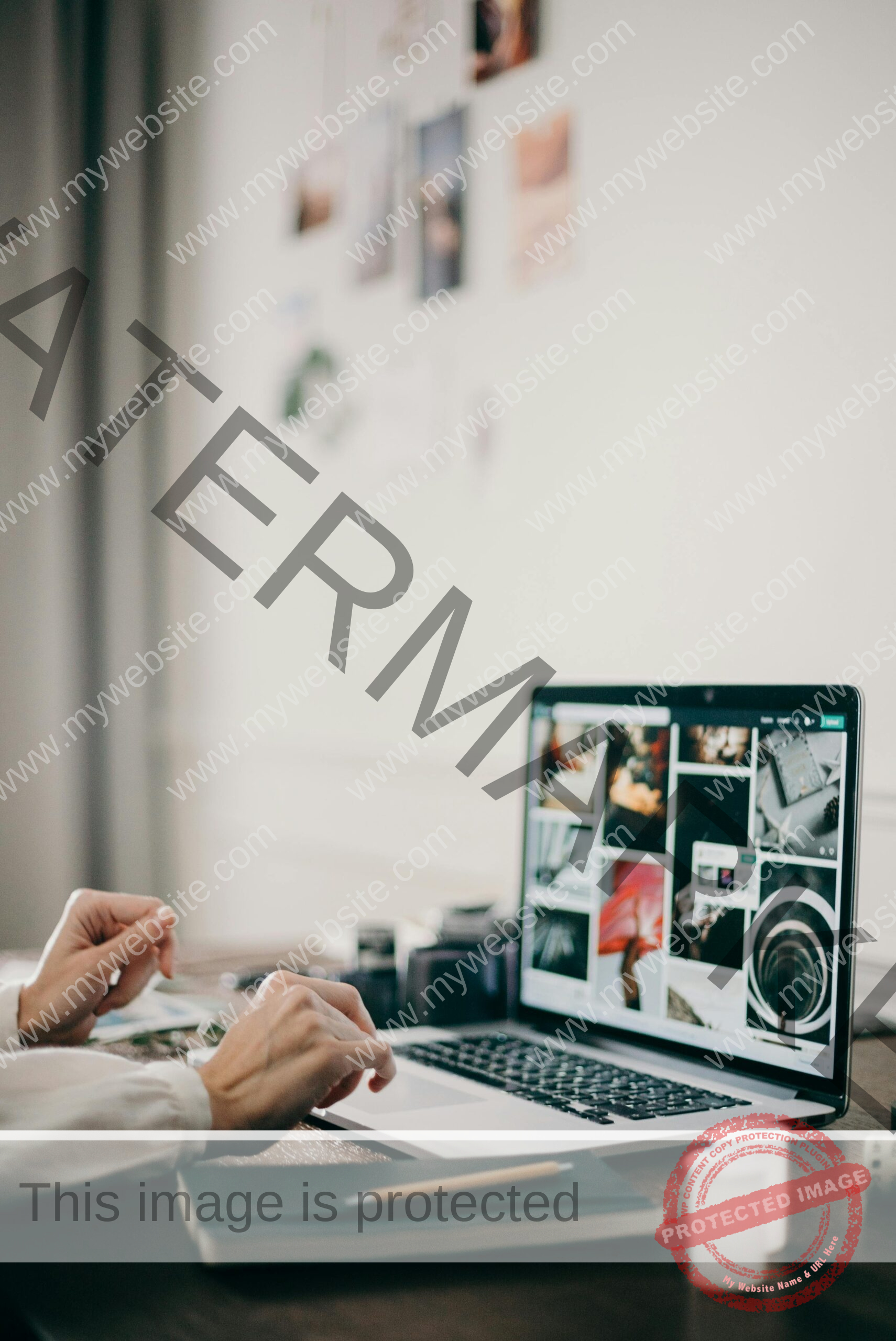 Hands working on laptop at a creative desk with photo editing on screen.