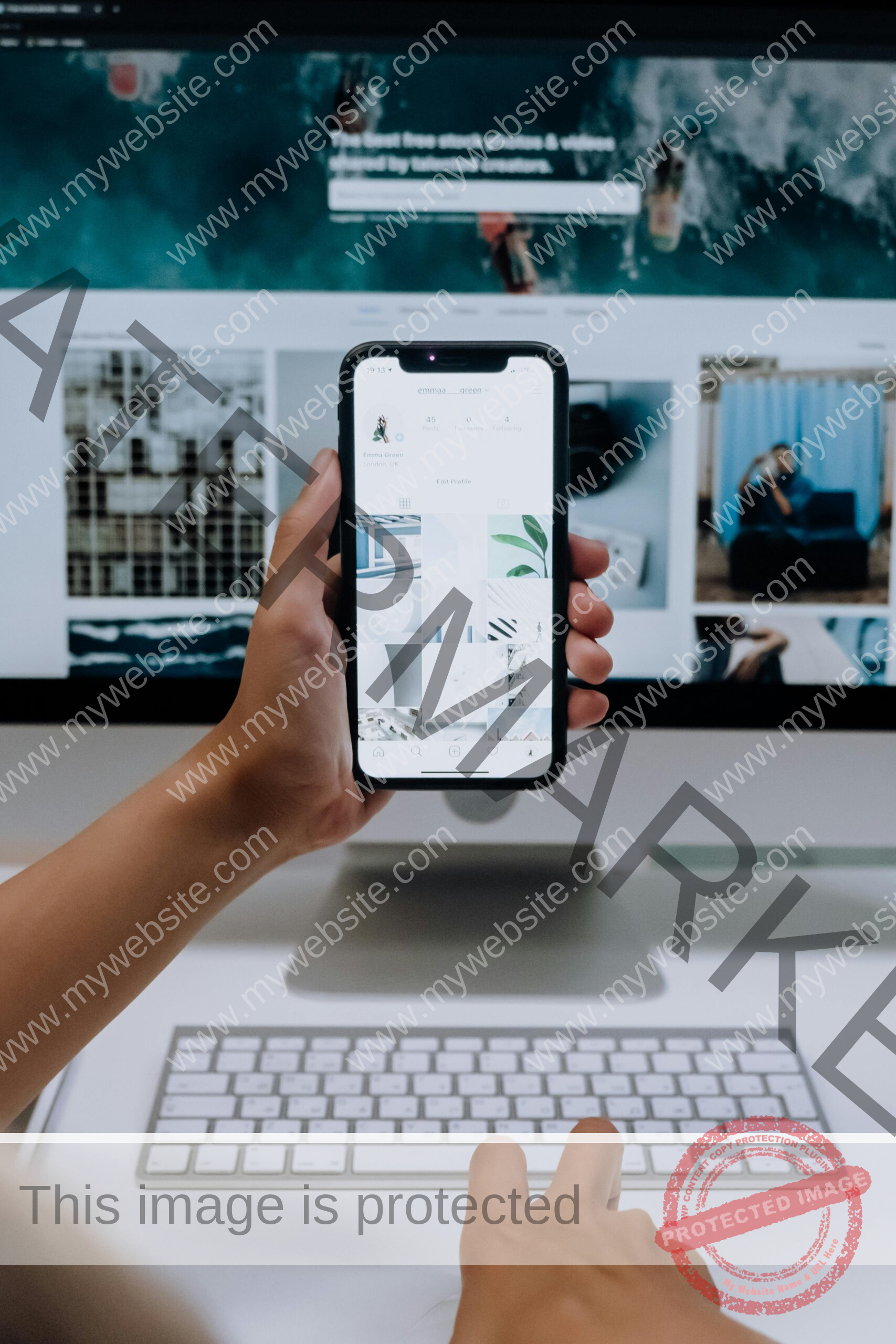 Person uses a smartphone in front of a computer screen displaying stock photos, showcasing modern technology use.